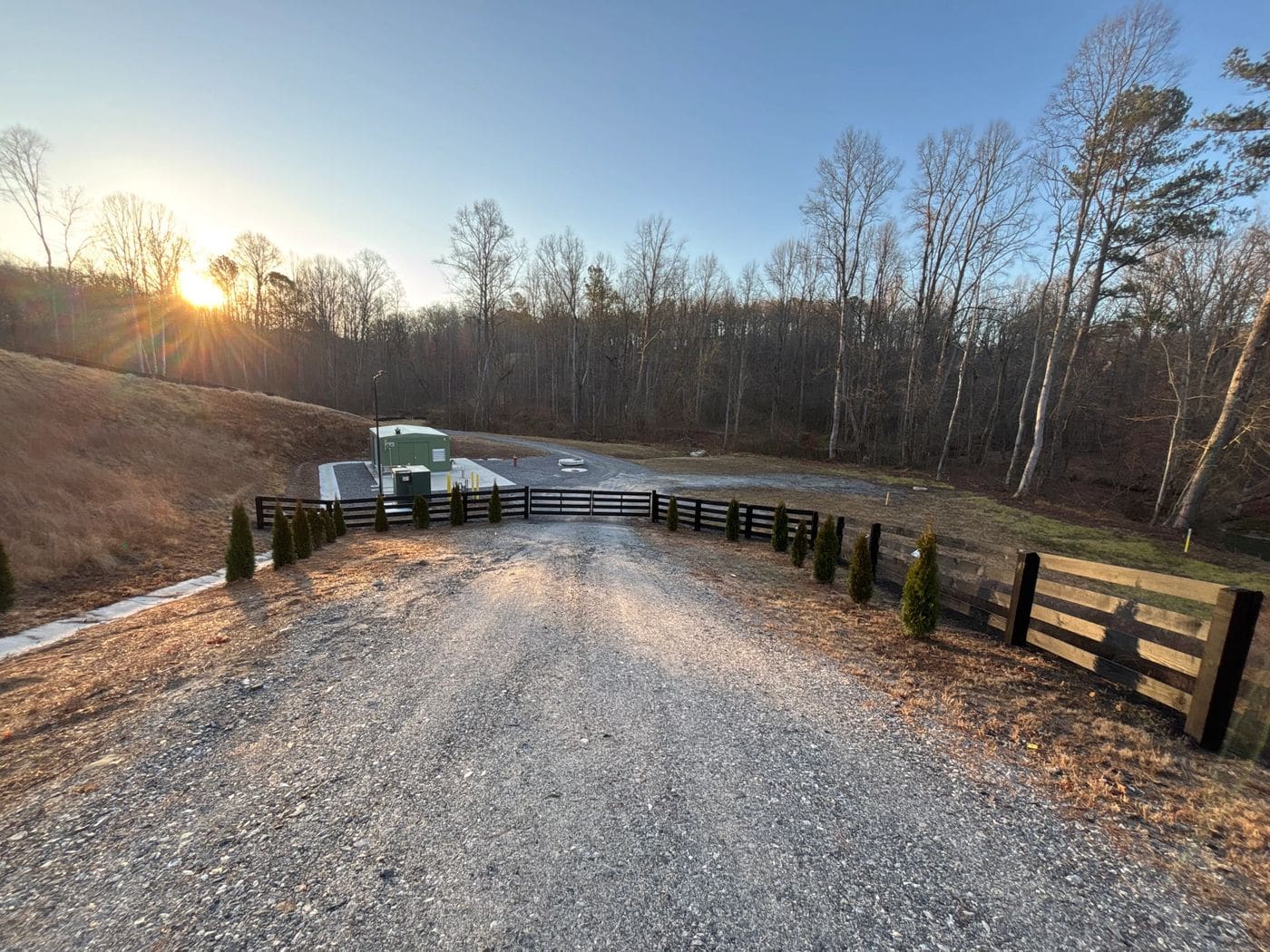 Fleming Fencing black four-board fence lining a rural driveway at sunrise in north Georgia