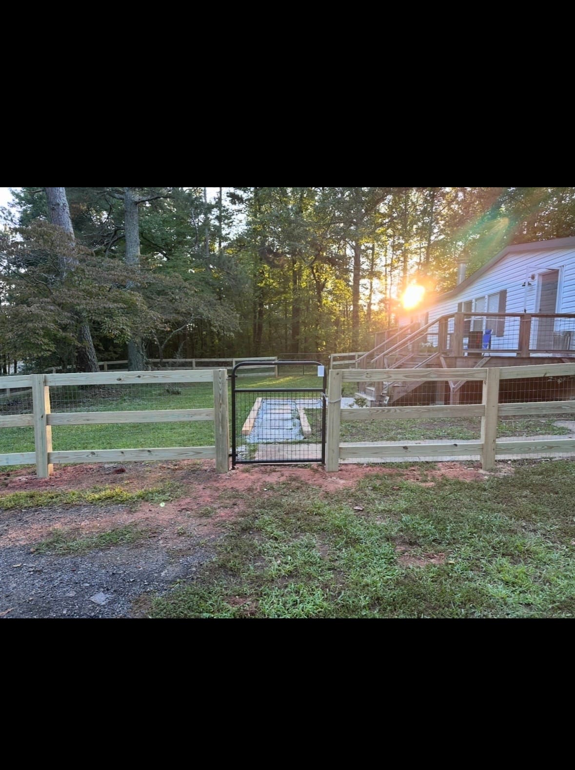 Wood split-rail fence with a black metal walk gate and farm entrance installed by Fleming Fencing in north Georgia